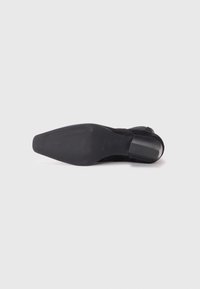Sorte nubuck høye hæler med en teksturert såle og en kvadratisk hæl. Skoen har et glatt og strømlinjeformet design med diskrete detaljer.