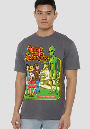 Man wearing a gray shirt showing children cautiously greeting a green alien with flying saucer and text "Don’t Talk to Strangers, Safety Education."
