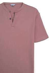 Maglietta corta a maniche corte di colore rosa chiaro con scollatura henley, due bottoni decorativi e un tessuto testurizzato. Il design presenta una vestibilità classica.