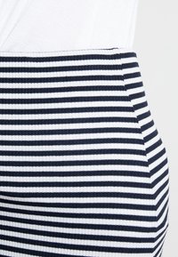 Námořnická a bílá pruhovaná žebrovaná sukně s přiléhavým střihem. Tkanina má texturovaný povrch, který obsahuje střídající se široké a úzké pruhy.