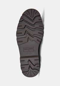 Smeđa gumena potplat s uzorkom cik-cak. Ima utisnutu oznaku brenda "PULL&BEAR" i veličinu "42" na potplatu.