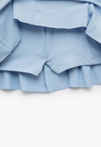 Jasnoniebieskie szorty z plisowanym wykończeniem. Wykonane z gładkiego materiału, z przeszytymi brzegami i ukrytym detalem szwu z tyłu.