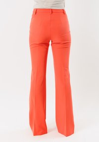 Pantaloni a campana arancioni vivaci con una finitura in tessuto liscia, cuciture su misura e due tasche posteriori, caratterizzati da una vita alta.
