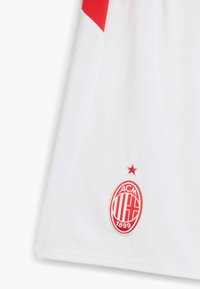 Camiseta del AC Milan en blanco con detalles en rojo, con el emblema del club que presenta una estrella y "ACM 1899" en la parte inferior.
