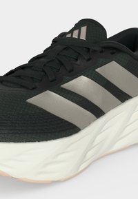 Μαύρο και γκρι αθλητικό παπούτσι με τρεις γκρι ρίγες στο πλάι και παχύ λευκό πάτο, με μαύρα κορδόνια και επενδυμένο γιακά.