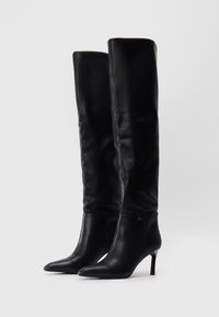 Zwarte leren over-de-knie laarzen metpuntige neuzen en een stilettohak. Kenmerkt zich door een gladde textuur en een minimalistisch ontwerp met branding.