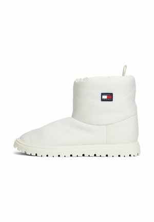 White padded ankle boot with a round toe, textured rubber sole, and a small logo patch in navy, red, and white on the side.