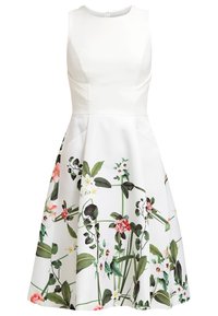 Robe blanche sans manches avec imprimés floraux en rose, vert et jaune, dotée d'un corsage ajusté et d'une jupe évasée. Fabriquée en tissu lisse.