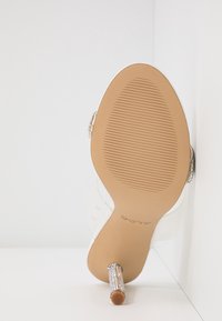 Vue de la semelle d'une chaussure à talon haut beige avec un talon aiguille recouvert de strass et le nom de la marque ALDO sur la semelle.