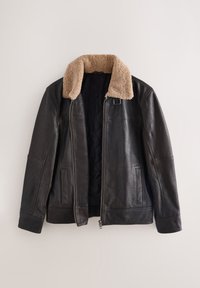 Veste en cuir noire avec col en shearling beige, fermeture éclair à l'avant et poches latérales, présentée sur un fond clair uni.