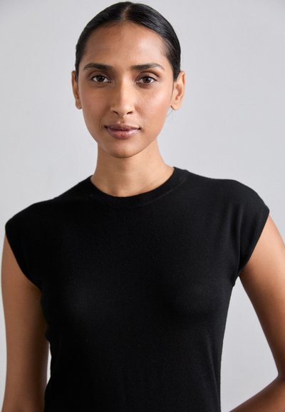 Black short-sleeve fitted top made of a soft, ribbed material. The neckline is round, and the fabric appears slightly sheer in some areas.