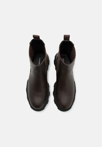 Bottines en cuir marron avec une finition lisse, des panneaux élastiques sur les côtés, une languette et une semelle en caoutchouc noir durable.