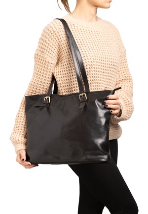 Sac fourre-tout en cuir noir avec deux anses, accents en métal doré et texture lisse. Le sac est de forme rectangulaire.