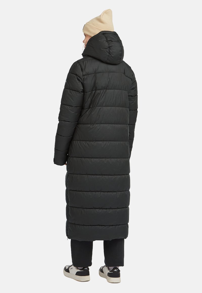 Musta puhvitakki, jossa on pitkä, ylisuurikokoinen muotoilu ja vaakasuora ompelu, mukana huppu ja sileä pinta. Yhdistelty mustien housujen ja tennareiden kanssa.