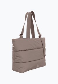 Gepolsterte taupefarbene Tragetasche mit breiten, verstellbaren Schulterriemen und dezentem Logo in der unteren Ecke, vor weißem Hintergrund dargestellt.
