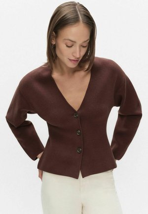 Brun stickad kofta med djup V-ringning, fem knappar framtill och figursydd silhuett. Långa ärmar och slät textur med minimala detaljer.