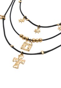 Czarny naszyjnik z sznurkiem, zdobiony złotymi metalowymi akcentami, w tym krzyżem, zamkiem i gwiazdą, z kulistymi złotymi koralikami wplecionymi między elementy.