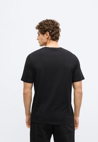 Μαύρο κοντομάνικο T-shirt από βαμβακερό μείγμα, με στρογγυλή λαιμόκοψη και ίσιο τελείωμα. Λείος υφασμάτινος, μινιμαλιστικός σχεδιασμός, κατάλληλο για casual εμφάνιση.