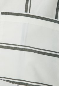 Paski w białym i ciemnoszarym kolorze, z kieszenią z kontrastowymi detalami szwów. Miękka tekstura, lekkki materiał.