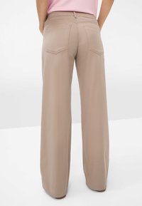 Weite, beige Hose mit glatter Textur, ausgestattet mit zwei Gesäßtaschen und einem entspannten Schnitt, der für Komfort und Bewegungsfreiheit sorgt.