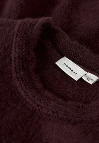 Bordový pletený svetr s měkkým, strukturovaným povrchem a kulatým výstřihem; obsahuje bílou etiketu s nápisem "name it" a informacemi o velikosti.