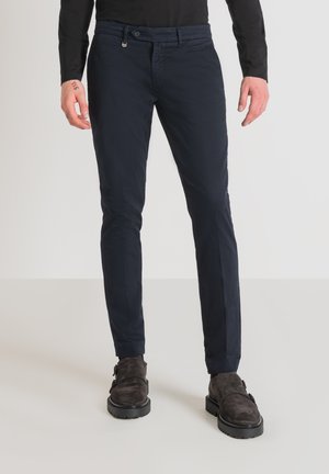 Pantaloni blu navy in vestibilità slim, realizzati in cotone con una superficie liscia. Presentano una chiusura a bottoni e un design a cinque tasche.