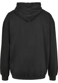 Sweat à capuche noir surdimensionné avec manches longues, capuche attachée, poignets et ourlet côtelés, vu de dos.