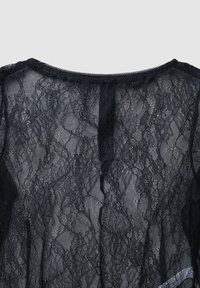 Top in pizzo nero con motivi floreali intricati, texture semitrasparente, scollatura rotonda e maniche corte. Dettagli includono un accento in nastro di raso.