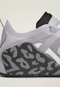 Světle šedá sportovní obuv s texturovanou černou podrážkou s proužkovaným leopardím vzorem a přiléhavým elastickým designem v oblasti kotníku.