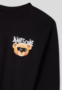 Felpa nera con grafica di un orso con occhiali da sole e la parola "AWESOME" in bianco sopra. Tessuto morbido e texturizzato.