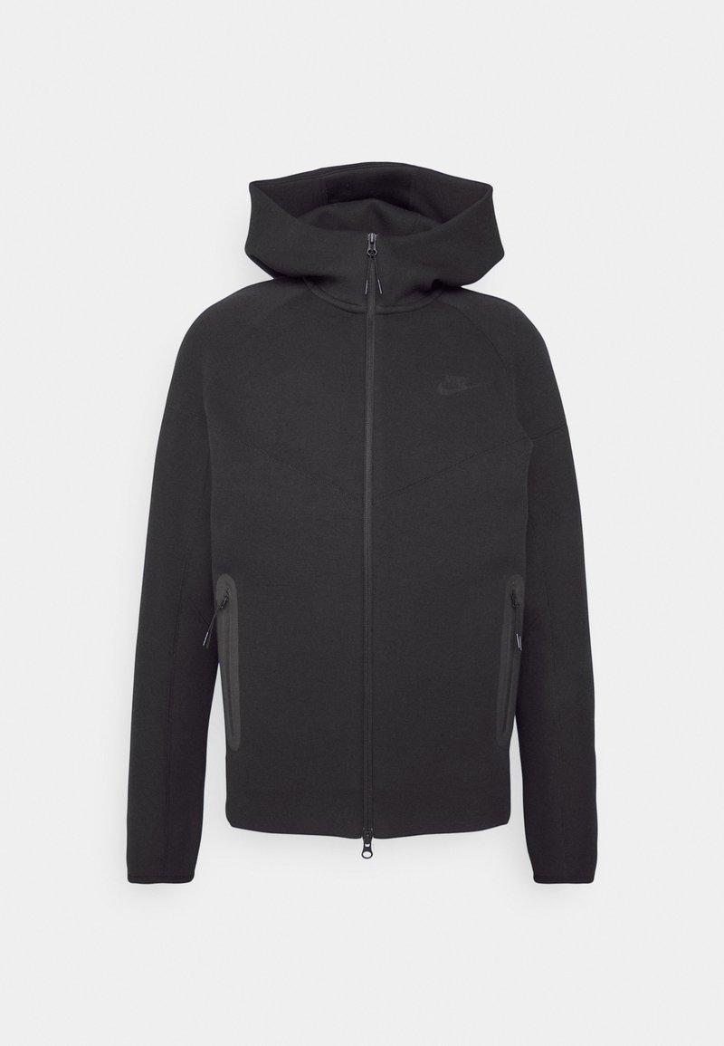 Svart sweatshirt med hög krage, dragkedja framtill, två sidofickor och en diskret Nike-logga på bröstet. Tillverkad av mjukt, ogenomskinligt material.