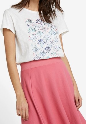 Weißes Kurzarmhemd mit buntem abstraktem Fächer-Muster, in einen hoch taillierten pinken Rock gesteckt, gezeigt vom Mitteltorso abwärts.