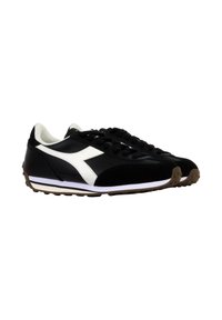 Scarpe da ginnastica nere con accenti bianchi. Realizzate in pelle e suede, presentano un design con lacci e una suola in gomma testurizzata con un leggero tacco.