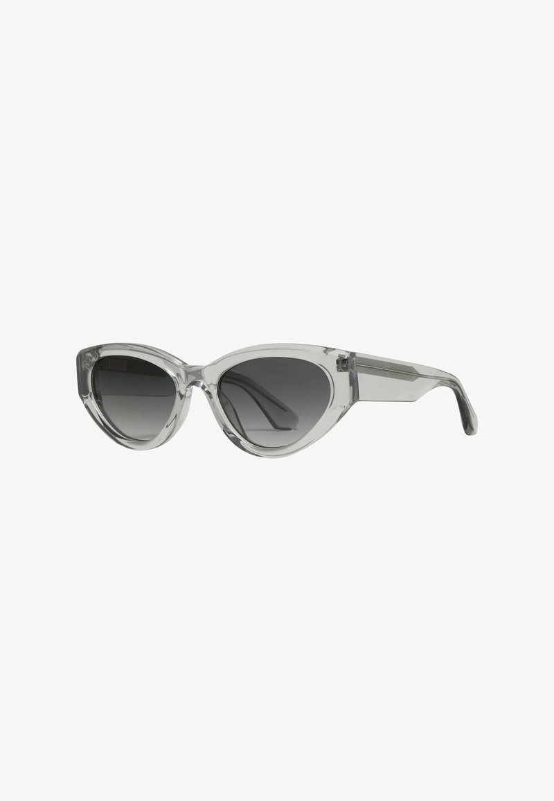Cat-eye solbriller med klare stel og mørke gradientlinser. Udstyret med glatte konturer og skrå arme med subtil detaljer ved hængslerne.