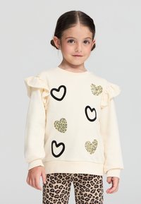 Felpa panna con maniche a volant, decorata con contorni neri a forma di cuori e dettagli glitterati a forma di cuore. Abbinata a leggings con stampa leopardata.