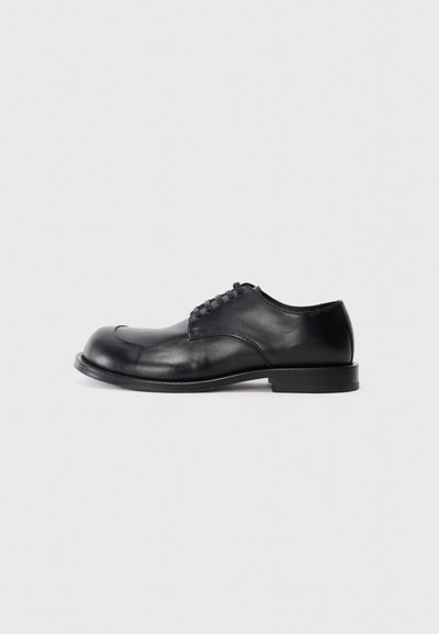 Zwarte leren oxford schoen met een ronde neus, vetersluiting, gladde textuur en een lichte hak. Eenvoudige silhouet met minimale details.