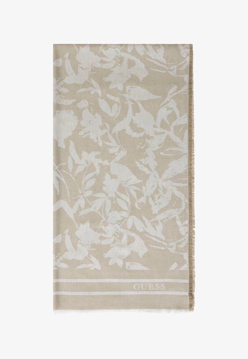 Écharpe beige avec motif floral blanc, bords frangés et logo "GUESS" près de la bordure inférieure.