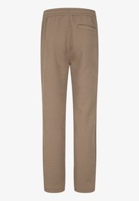 Ljusbruna byxor med en strukturerad zigzagmönster, elastisk midja och en enda bakfickan. Raka ben.