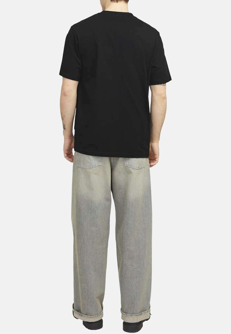 Camiseta de algodón negra combinada con jeans de pierna ancha en gris claro. La camiseta tiene un cuello redondo clásico y mangas cortas. Detalles mínimos.