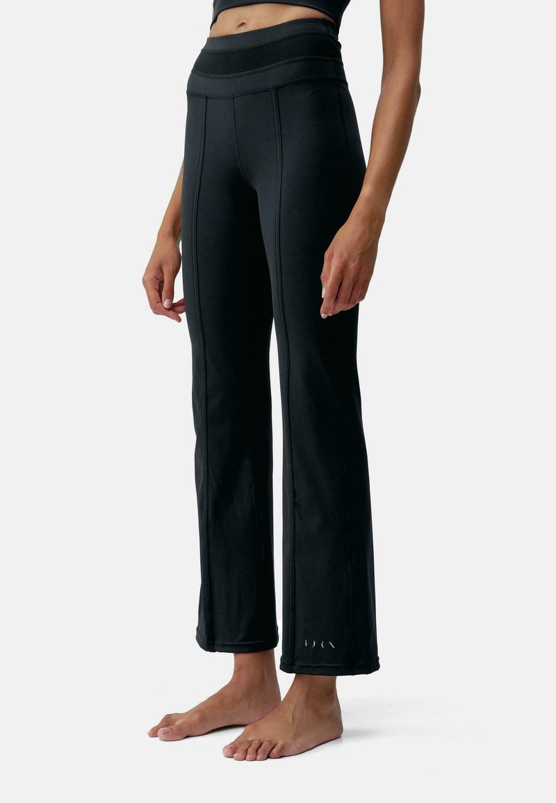Fekete sportleggings magas derékkal, sima textúrával és kontrasztos varrásokkal. Nyitott szár és apró logó részlet.