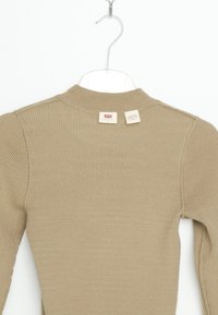 Beige gerippter Langarmshirt mit hohem Kragen, das eine Nahtdetails auf den Schultern und zwei Markenetiketten auf der Rückseite aufweist.