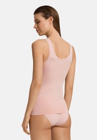 Top in rosa realizzato in tessuto liscio e elasticizzato con design a schiena scoperta, abbinato con brasiliani rosa coordinati. Presenta cuciture minime e una silhouette aderente.