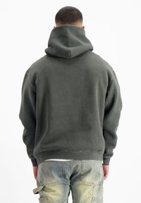 Donkergrijze hoodie met een grote capuchon, ribbelmanchetten en -zoom; zachte textuur; gedragen met lichtblauwe cargojjeans met opgestikte zakken.