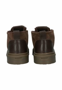 Botas tobilleras de ante marrón con acentos de cuero, lengüetas de tirón y una suela de goma texturizada. Presentan un diseño minimalista y un logo embossado.