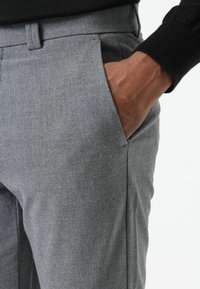 Grijze op maat gemaakte broek met een gestructureerde stof, voorzien van een zijzak en een platte voorkant. De tailleband vult de algehele uitstraling aan.