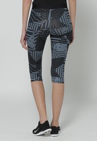 Czarne i szare legginsy z różnymi geometrycznymi wzorami i teksturami, o długości do połowy łydki i z elastycznym paskiem w talii.