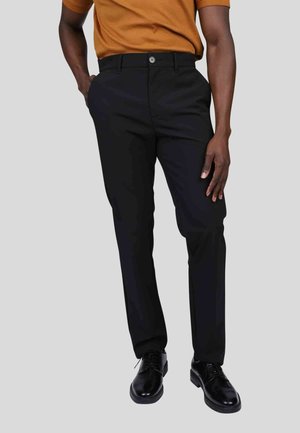 Pantalons noirs avec une coupe droite, dotés d'une fermeture à bouton à l'avant et de poches latérales, associés à des chaussures habillées noires.