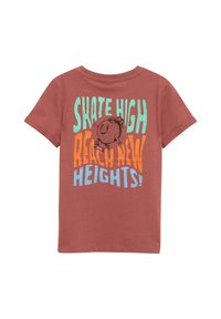 Roestkleurig t-shirt met korte mouwen, voorzien van een grafische print van een cartoonfiguur en de tekst: "SKATE HIGH REACH NEW HEIGHTS!" in blauw en oranje.