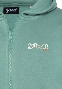 Felpa con zip verde menta realizzata in tessuto a coste. Presenta una chiusura frontale con zip, un cappuccio e un logo bianco con accenti rossi sul petto.