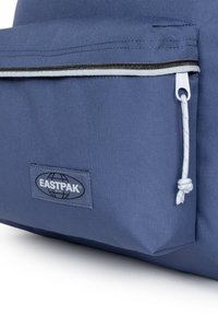Tummansininen Eastpak-reppu, jossa on teksturoitu kangas, etuosan vetoketjullinen tasku musta-valkoisella korostuksella ja logopatch.
